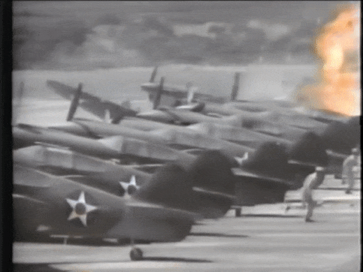 An animated gif showing a plane crashing into replicas, causing explosions and sending stunt men running