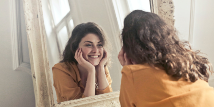 A woman practicing her smile in a mirror.